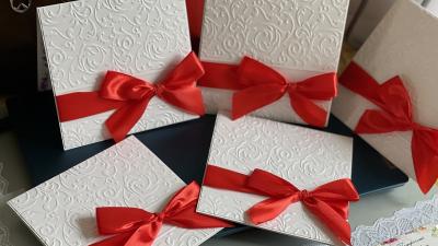 White textured cards with red ribbons on a dark surface